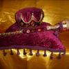 Courage Dancer set $175. 18" sq. pillow of velvety Crimson imprinted fabric, trimmed in tassel beaded trim; topped with golden crown, gold metallic rope and tasseled trim; and Amethyst and Cerise jewels. 4' scepter topped with gold sequins and matching trim.